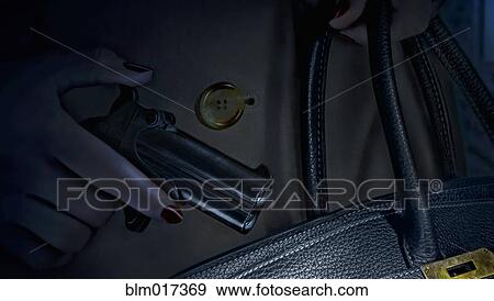 Woman putting pistol in purse View Large Photo Image Stock Photo - Woman putting pistol in purse. Fotosearch