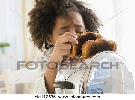 Stock Photograph - African American girl burning toast in toaster. Fotosearch