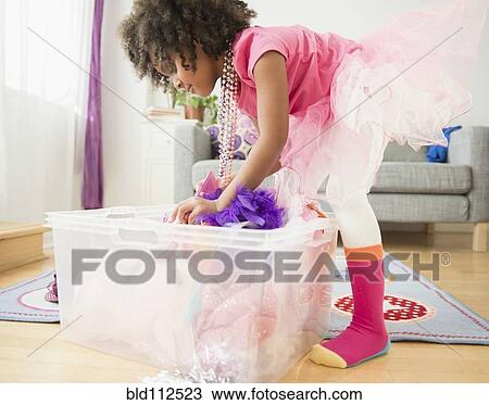 Stock Image - African American girl digging in clothes bin. Fotosearch