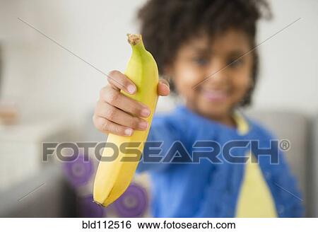 African American girl holding banana on sofa View Large Photo Image Stock Photograph - African American girl holding banana on sofa. Fotosearch