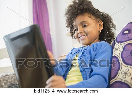 African American girl using tablet computer on sofa View Large Photo Image Picture - African American girl using tablet computer on sofa. Fotosearch
