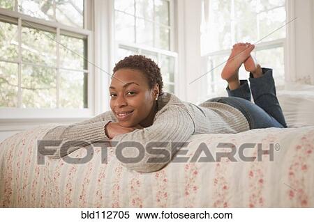 Stock Photography - African American woman laying in bed. Fotosearch
