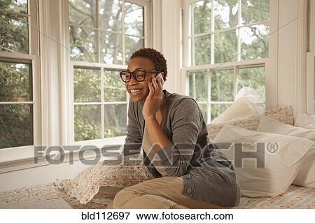 African American woman sitting in bed talking on cell phone View Large Photo Image Stock Photo - African American woman sitting in bed talking on cell phone. Fotosearch