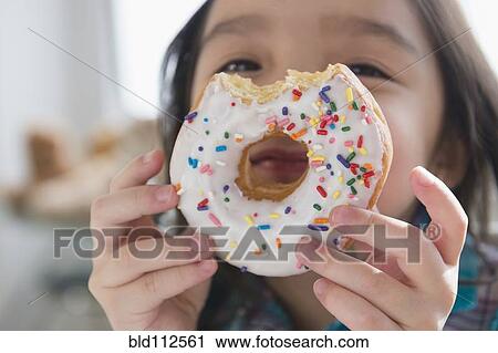 Stock Image - Asian girl peeking through donut hole. Fotosearch