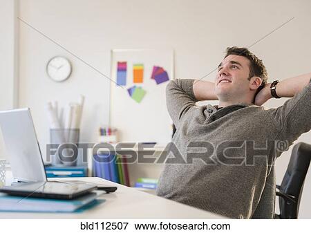 Businessman relaxing at desk in office View Large Photo Image Stock Photo - Businessman relaxing at desk in office. Fotosearch