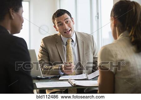 Businessman talking with clients at desk View Large Photo Image Stock Photograph - Businessman talking with clients at desk. Fotosearch
