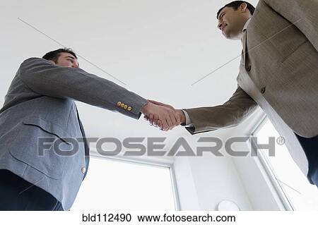 Businessmen shaking hands in office View Large Photo Image Stock Image - Businessmen shaking hands in office. Fotosearch