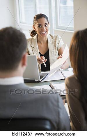 Stock Photo -  Businesswoman talking with clients at desk. Fotosearch