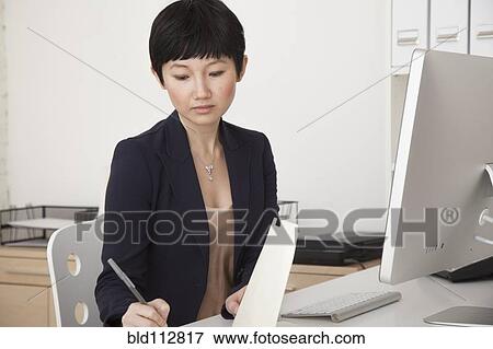 Stock Photo - Businesswoman working at desk in office. Fotosearch