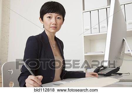 Stock Photo - Businesswoman working at desk in office. Fotosearch