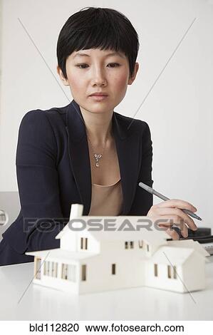 Stock Image - Businesswoman working on model in office. Fotosearch