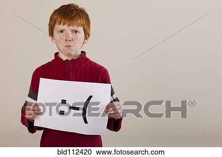 Stock Image - Caucasian boy holding card with sad face. Fotosearch
