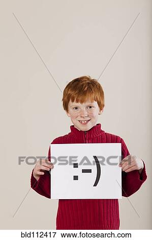 Stock Photo - Caucasian boy holding card with smiley face. Fotosearch
