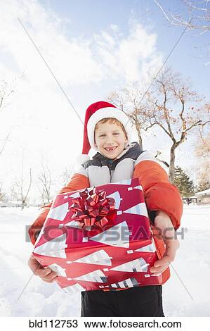 Caucasian boy in Santa hat holding Christmas present View Large Photo Image Stock Image - Caucasian boy in Santa hat holding Christmas present. Fotosearch