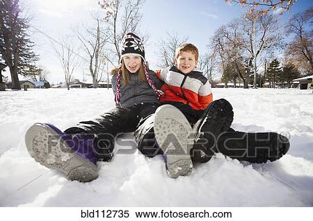 Stock Photography - Caucasian children sitting in snow outdoors. Fotosearch
