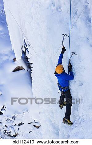 Stock Image - Caucasian climber scaling glacier. Fotosearch