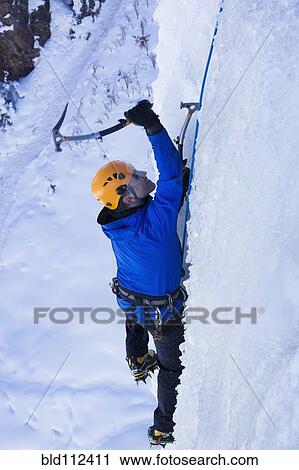 Stock Image - Caucasian climber scaling glacier. Fotosearch