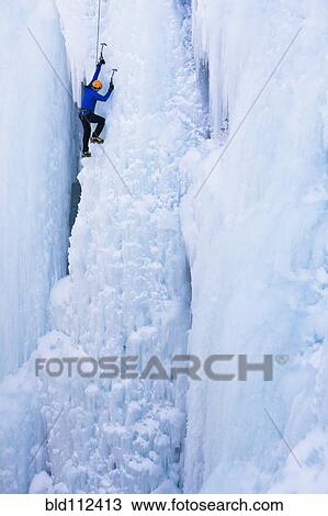 Stock Image - Caucasian climber scaling glacier. Fotosearch