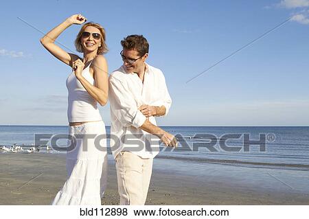 Stock Photo - Caucasian couple dancing on beach. Fotosearch