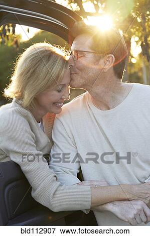 Caucasian couple kissing by car View Large Photo Image Stock Photo - Caucasian couple kissing by car. Fotosearch