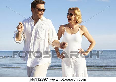 Stock Photo - Caucasian couple playing on beach. Fotosearch