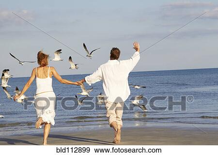 Stock Photo - Caucasian couple running on beach. Fotosearch