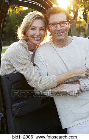 Stock Photograph - Caucasian couple smiling by car. Fotosearch