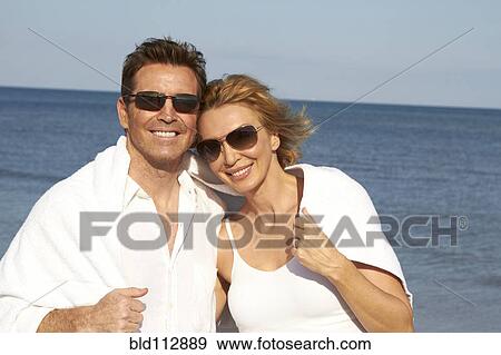 Stock Photo - Caucasian couple smiling on beach. Fotosearch