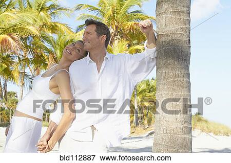Stock Photo - Caucasian couple smiling on tropical beach. Fotosearch