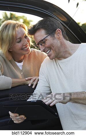 Picture - Caucasian couple using digital tablet by car. Fotosearch