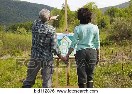 Stock Photograph - Caucasian couple visualizing house in rural landscape. Fotosearch