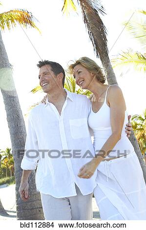 Picture - Caucasian couple walking on tropical beach. Fotosearch