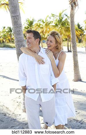 Stock Image - Caucasian couple walking on tropical beach. Fotosearch