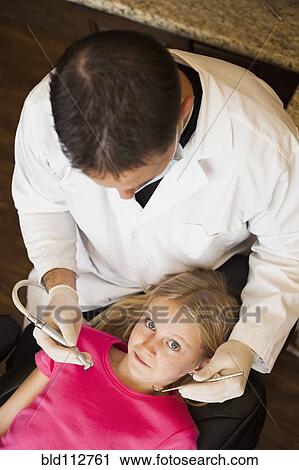 Caucasian dentist examining girl's teeth in office View Large Photo Image Stock Image - Caucasian dentist examining girl's teeth in office. Fotosearch