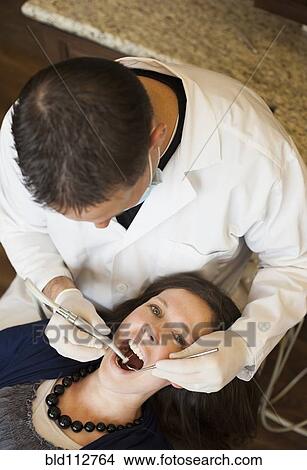 Caucasian dentist examining woman's teeth in office View Large Photo Image Picture - Caucasian dentist examining woman's teeth in office. Fotosearch