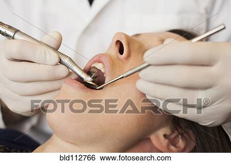 Stock Photograph - Caucasian dentist examining woman's teeth in office. Fotosearch