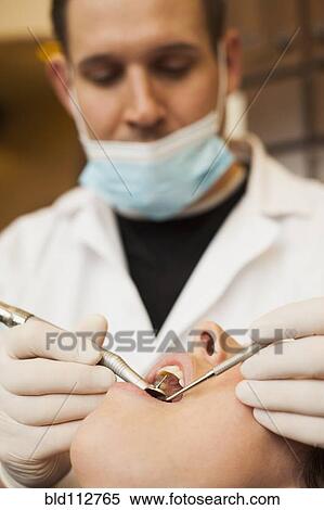Stock Photography - Caucasian dentist examining woman's teeth in office. Fotosearch