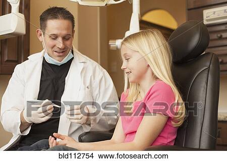 Picture - Caucasian dentist talking to girl in office. Fotosearch