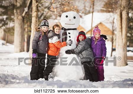 Stock Photography - Caucasian family building snowman in snow. Fotosearch