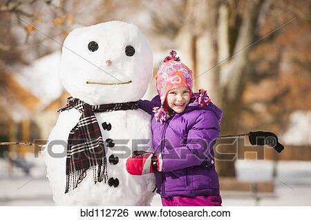 Caucasian girl building snowman in snow View Large Photo Image Stock Photograph - Caucasian girl building snowman in snow. Fotosearch