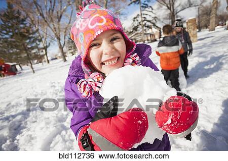 Stock Photograph - Caucasian girl holding snowball outdoors. Fotosearch