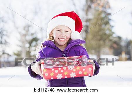 Caucasian girl in Santa hat holding Christmas present View Large Photo Image Stock Photo - Caucasian girl in Santa hat holding Christmas present. Fotosearch