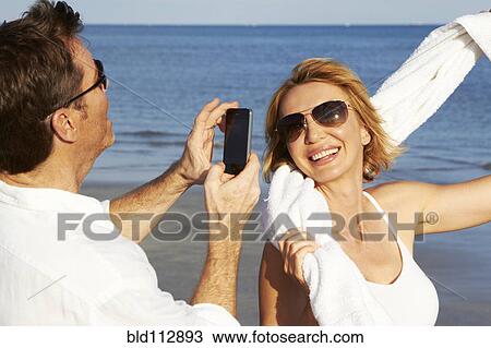 Caucasian man taking pictures of girlfriend on beach View Large Photo Image Stock Image - Caucasian man taking pictures of girlfriend on beach. Fotosearch