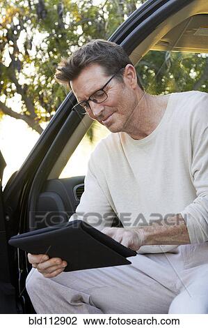 Stock Image - Caucasian man using digital tablet in car. Fotosearch