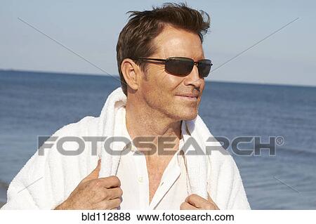 Stock Photo - Caucasian man walking on beach. Fotosearch