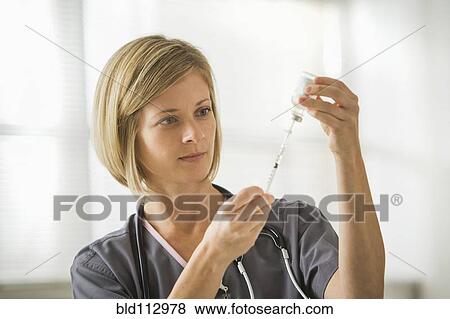 Stock Photo - Caucasian nurse filling syringe. Fotosearch