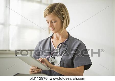 Stock Photograph - Caucasian nurse holding digital tablet. Fotosearch