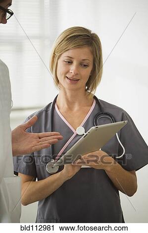 Stock Image - Caucasian nurse showing digital tablet to doctor. Fotosearch