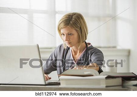 Picture - Caucasian nurse using laptop in doctor's office. Fotosearch