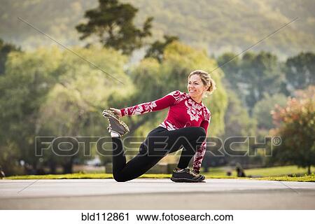Stock Image - Caucasian runner stretching in park. Fotosearch
